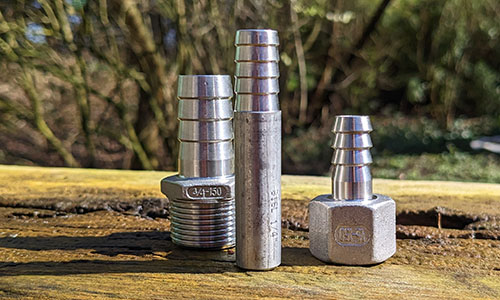 verschiedene Edelstahl Schlauchtüllen auf einem Baumstamm im Garten