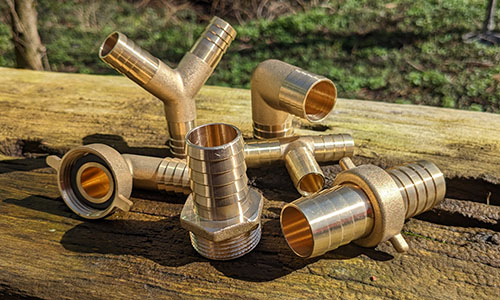 verschiedene Messing Schlauchtüllemn auf einem Baumstamm im Garten
