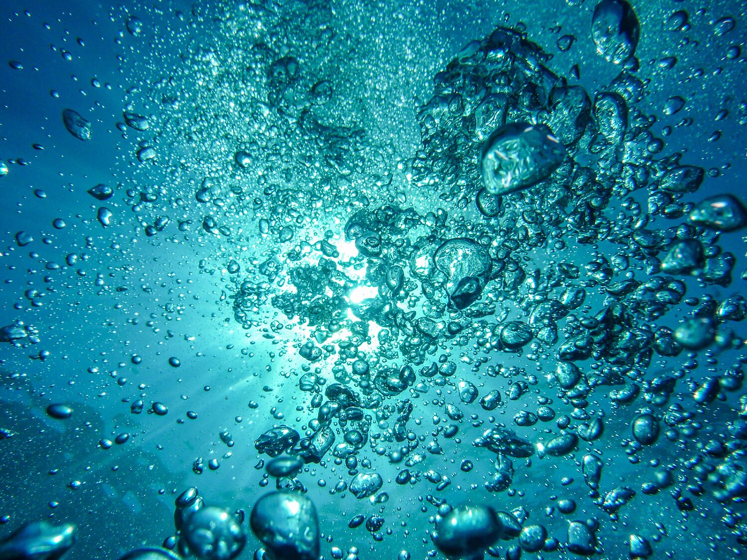 Unterwasseraufnahme von aufsteigenden Luftblasen im Wasser.