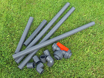 Verschiedene PVC-Rohre und Fittings auf einer Wiese.