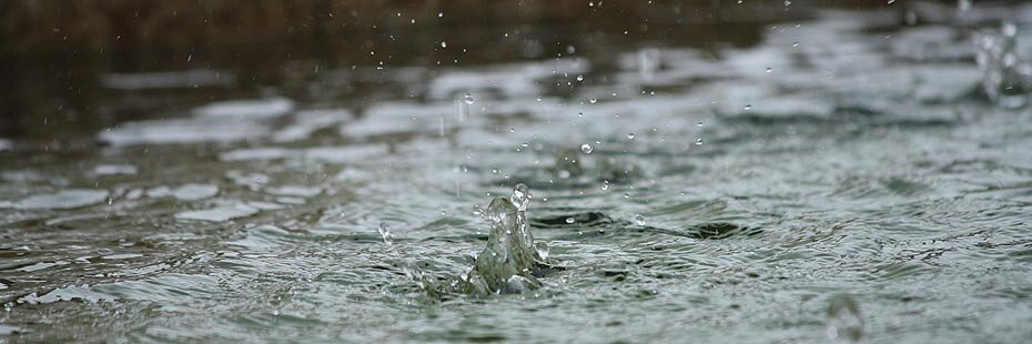Wasser in einer Pfütze bei Regen, mit einfallenden...