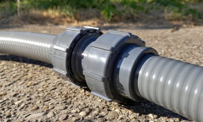 Eine Flaxfit Verschraubung, in die auf beiden Seiten ein Schlauch verschraubt wurde. Schlauch und Verschraubung liegen auf einer Straße. Nahaufnahme.